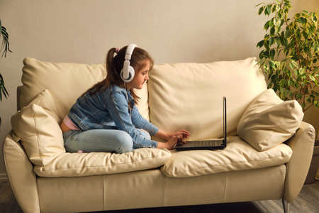 Kid girl with headphones looking video lessonの写真素材