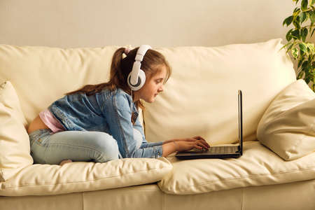 Kid girl with headphones looking video lessonの写真素材