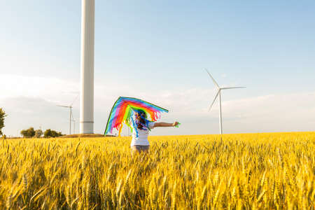Happy Little girl running in a wheat field with a kite in the summer.の写真素材