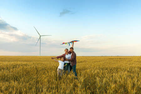 Happy family having fun with kite on the field.の写真素材