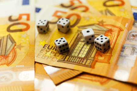 White Gaming dice and money on dark table.の写真素材