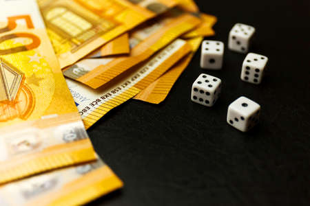 White Gaming dice and money on dark table.の写真素材