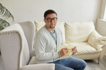 Friendly psychologist with clipboard, leaning at wall in office, empty spaceの写真素材