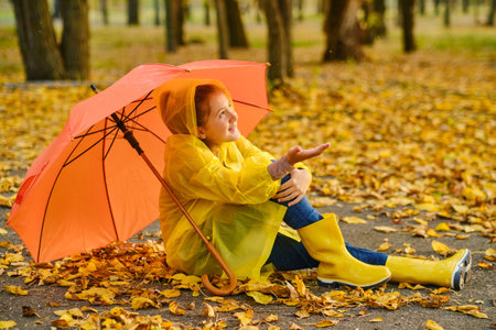 happy kid catching rain drops in Autumn parkの写真素材