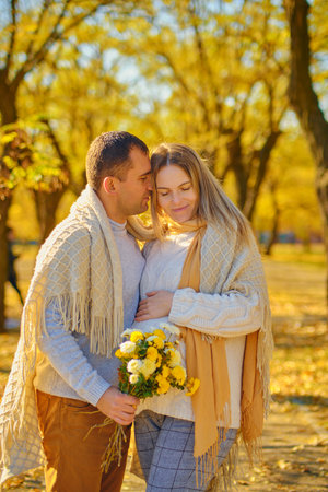 Pregnant woman and man at sunny warm autumn parkの写真素材