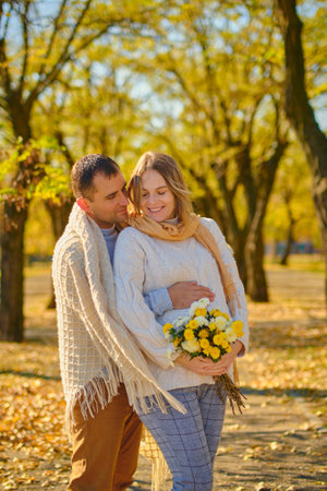 Pregnant woman and man at sunny warm autumn parkの写真素材