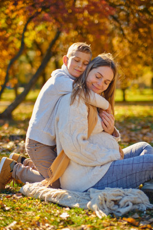 little son hugs his pregnant mom on the natureの写真素材