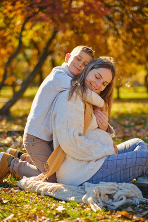 little son hugs his pregnant mom on the natureの写真素材