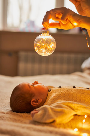 A newborn baby in a knitted babysuit lies on the bedの写真素材