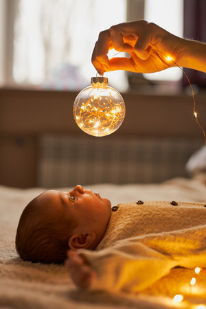 A newborn baby in a knitted babysuit lies on the bedの写真素材