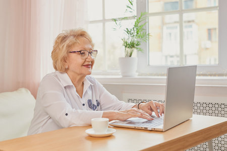 Happy mature middle aged elderly woman reading good news looking at laptopの写真素材