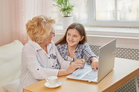 Adult granddaughter teaching her elderly grandmother to use laptopの写真素材