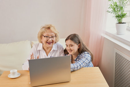 Adult granddaughter teaching her elderly grandmother to use laptopの写真素材