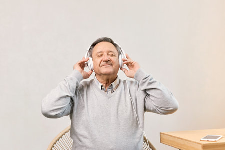 Senior man in living room wearing headphoneの写真素材