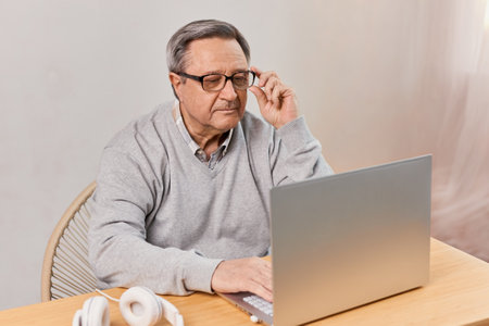 Senior man at home connected on laptop computer