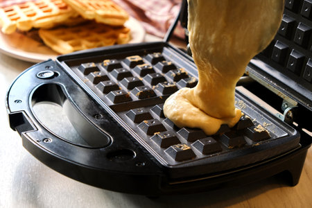 Liquid dough poured waffle iron machine to prepare sweat Belgian waffle dessert.の写真素材