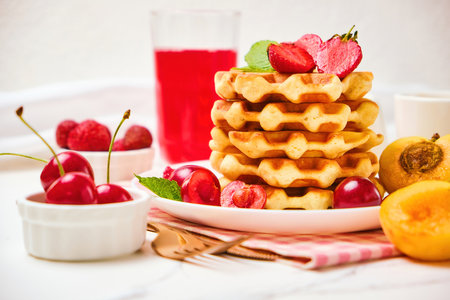 Belgian waffles with strawberries, apricots, cherries, juiceの写真素材