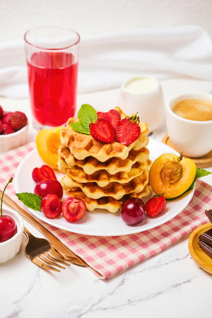 Belgian waffles with strawberries, apricots, cherries, juiceの写真素材