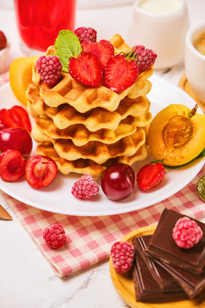 Belgian waffles with strawberries, apricots, cherries, juice and a cup of black coffeeの写真素材