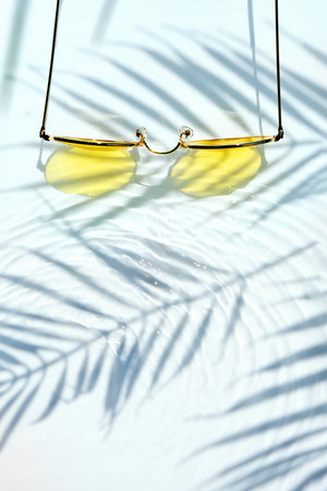 Summer flat lay with yellow sunglasses on water backgroundの写真素材