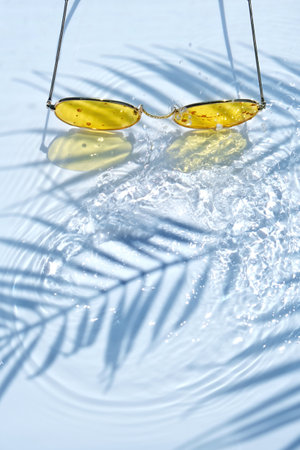 Summer flat lay with yellow sunglasses on water backgroundの写真素材