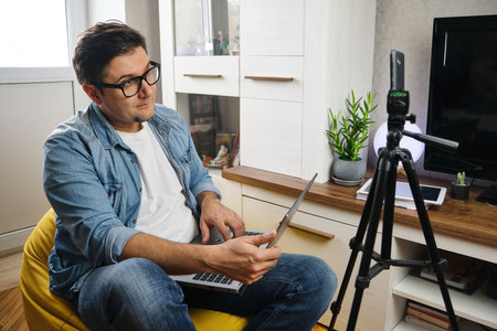 Video blogger recording content to channel at home before smartphone fixed on tripodの写真素材