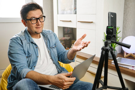 Video blogger recording content to channel at home before smartphone fixed on tripodの写真素材