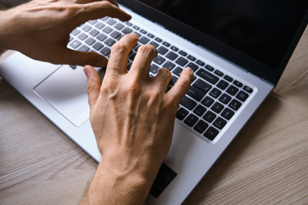 Mans hands typing on laptop keyboard top viewの写真素材