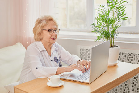 Happy mature woman reading good news looking at laptop, watching onlineの写真素材