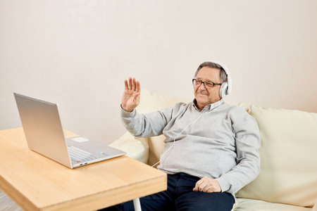 Older man wear headset start videoconference at home.の写真素材