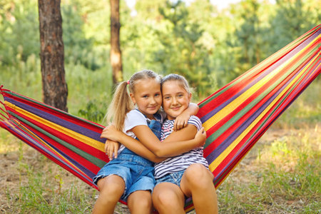 Kids relax in colorful rainbow hammock in garden.の写真素材