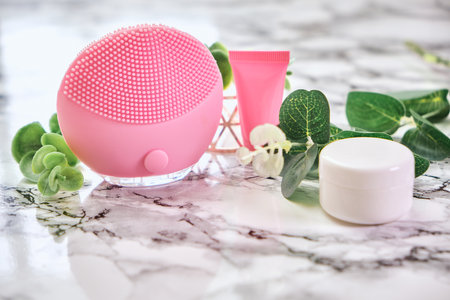 Electric facial massager and cream on a marble backgroundの写真素材