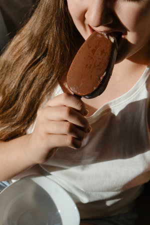 Kid Girl eating chocolate popsicle ice cream, close-up, unrecognizable child
