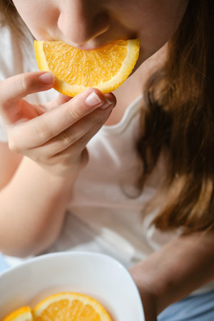 A kid girl eats an orange slice, close-up, without eyes. Vitamin nutrition, fruitsの写真素材