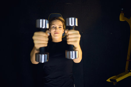 Top view portrait of A beautiful athletic middle-aged blond woman in sportswear in the fitness room raises dumbbells lying downの写真素材