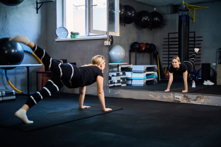 Young attractive sportive woman wearing activewear doing exercises at GYM, working out indoors, healthy active lifestyle conceptの写真素材