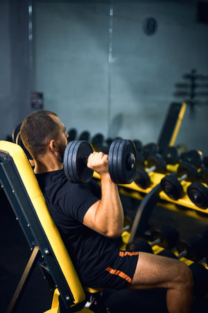 Middle age man with dumbbells flexing muscles in gym - sport, fitness, bodybuilding, lifestyle and people conceptの写真素材