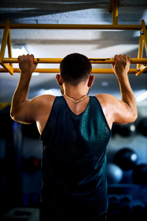 Back view of a strong man doing pull ups in a gym. Fitness and bodybuilding training health...