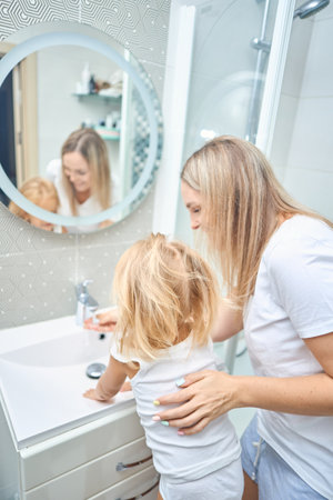 Mom teaches her child hands washing with soap in bathroomの写真素材
