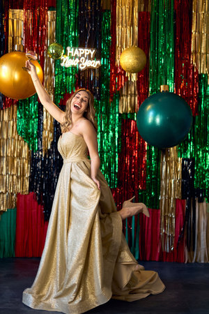 Party, luxury and people concept: Glamour women in luxury glitter golden dress drinking champagne and having fun posing over sparkly background. Happy New Year.の写真素材