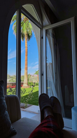 Female 's feet relaxing on the bed with luxury room and beautiful stunning Exotic view with palms