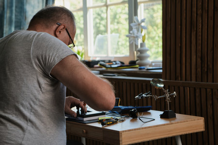 Mature Men wearing denim shirt working with electronic components at his home officeの写真素材