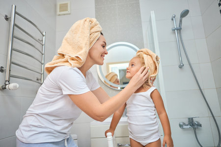 Happy family in the bathroom. mother of a child daughter with a towel dry hairの写真素材