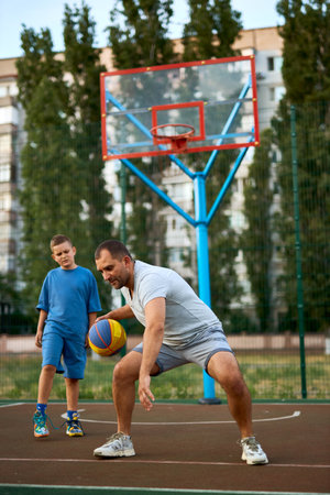 Basketball, family and teaching sport. Father and son training on a court outside for playing basketball and fun. Sporty man and kid doing exercise and workout playing a game for health and recreationの写真素材
