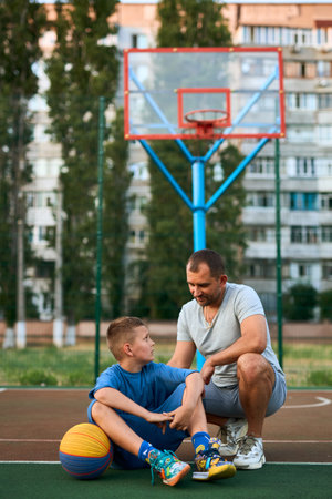 Portrait of happy Father and son after playing basketball together at the basketball court. Father and coach praises and supports his son for training, sporty lifestyle, training, restの写真素材