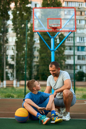 Portrait of happy Father and son after playing basketball together at the basketball court. Father and coach praises and supports his son for training, sporty lifestyle, training, restの写真素材
