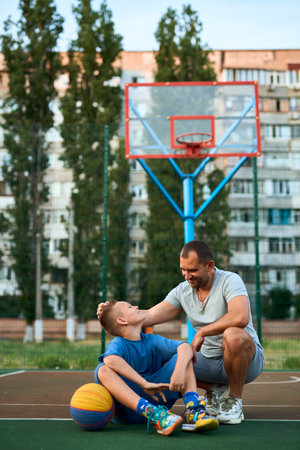 Portrait of happy Father and son after playing basketball together at the basketball court. Father and coach praises and supports his son for training, sporty lifestyle, training, restの写真素材