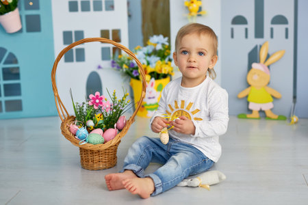 Beautiful child with painting eggs. Family home decoration, colorful Easter eggs and flowers. Home...