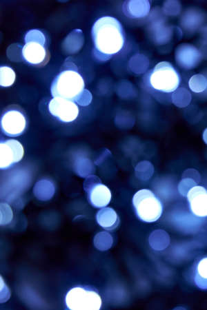 Cold blue color. Defocused bokeh christmas white and bllue lights on black background. Blurred abstract blue glitter texture. Blur bokeh glitter wallpaper for Christmas, New year or festival background.の写真素材