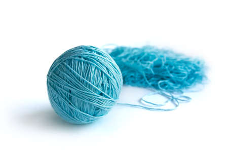 A ball of blue fine cotton yarn in the process of winding, isolated on the white background. Tangled...